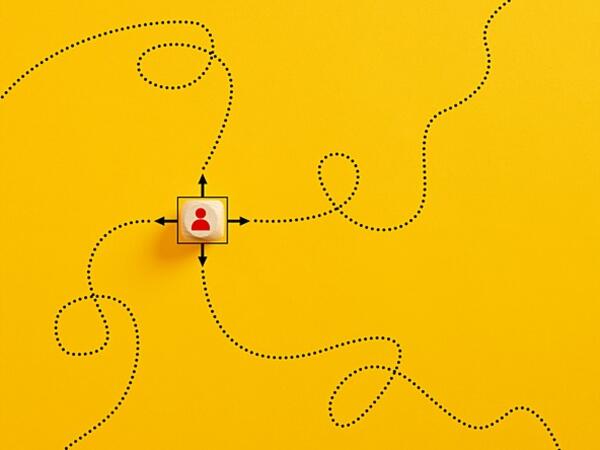 wooden cube with silhouette of person and arrows pointing in four directions to dotted swirling lines